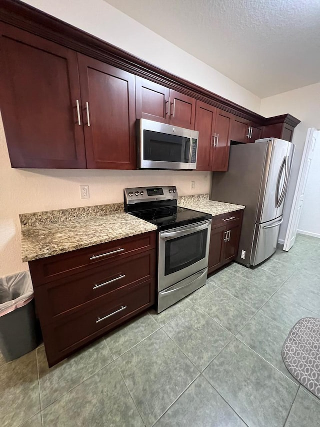 kitchen featuring light stone counters, a textured ceiling, and appliances with stainless steel finishes