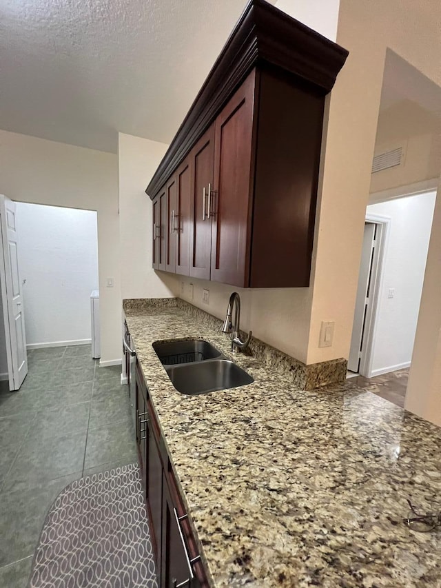 kitchen with sink, dark tile patterned floors, and light stone countertops