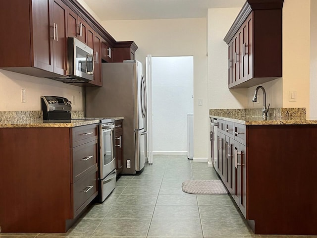 kitchen with light stone countertops, light tile patterned floors, appliances with stainless steel finishes, and sink