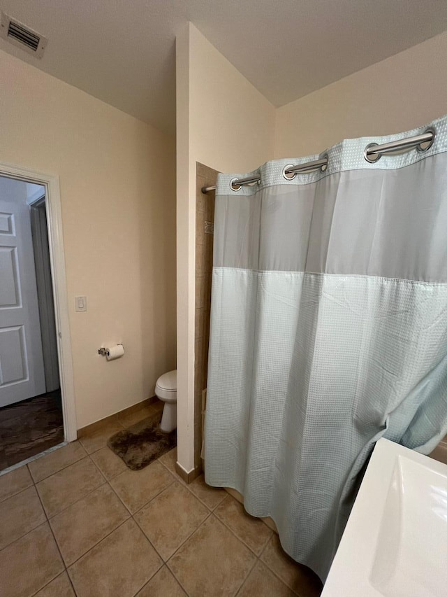 bathroom with toilet, tile patterned floors, and a shower with curtain