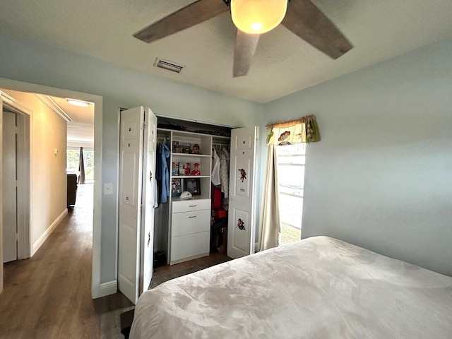 bedroom with dark wood-type flooring, ceiling fan, and a closet