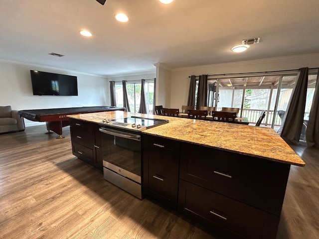 kitchen featuring light stone counters, stainless steel electric stove, ornamental molding, and a center island