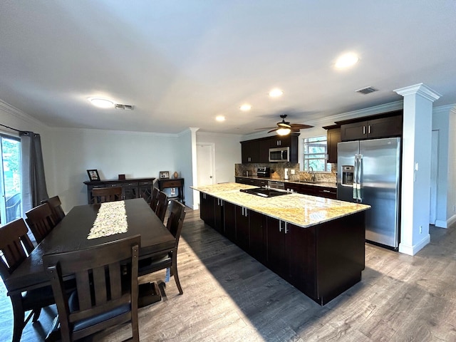 kitchen featuring sink, a center island, light stone counters, stainless steel appliances, and light hardwood / wood-style flooring