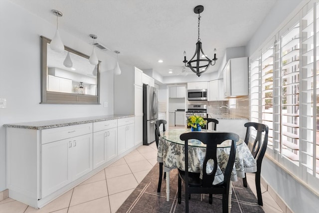 tiled dining space featuring sink, a notable chandelier, and a textured ceiling