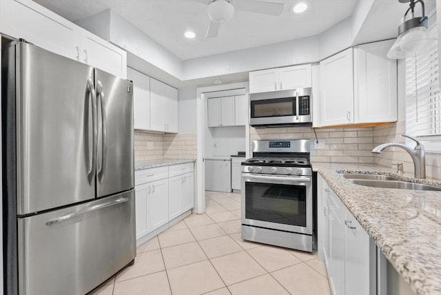 kitchen with tasteful backsplash, sink, white cabinets, stainless steel appliances, and light stone counters