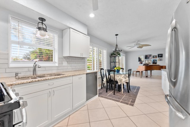 kitchen featuring appliances with stainless steel finishes, white cabinetry, sink, pendant lighting, and light tile patterned flooring