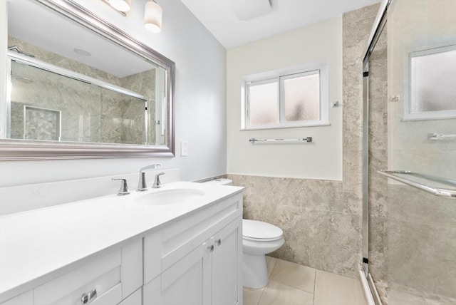 bathroom with tile patterned flooring, vanity, tile walls, toilet, and a shower with shower door