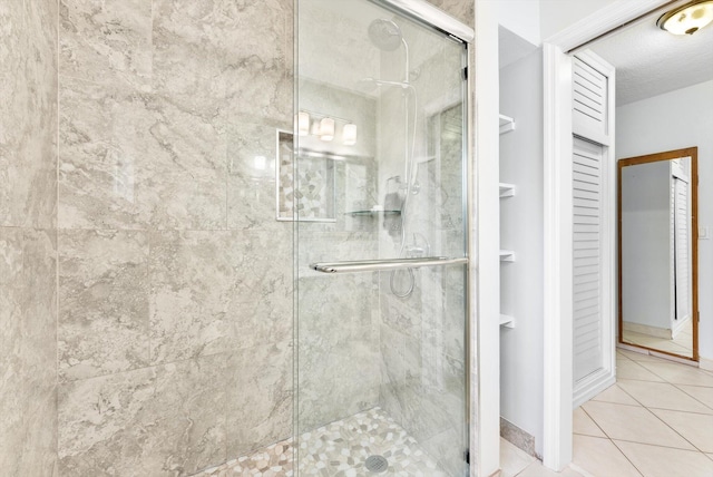 bathroom with a textured ceiling, a shower with door, and tile patterned flooring