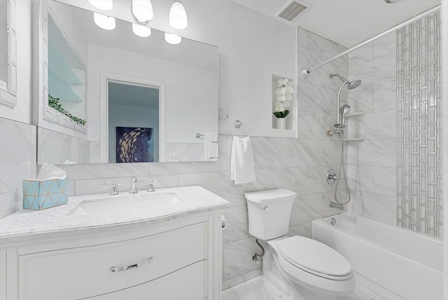 full bathroom with tile walls, toilet, vanity, and tiled shower / bath combo