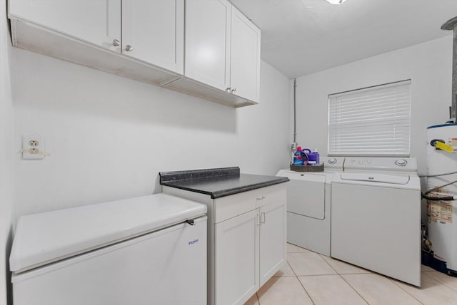 laundry room featuring water heater, cabinets, independent washer and dryer, and light tile patterned flooring