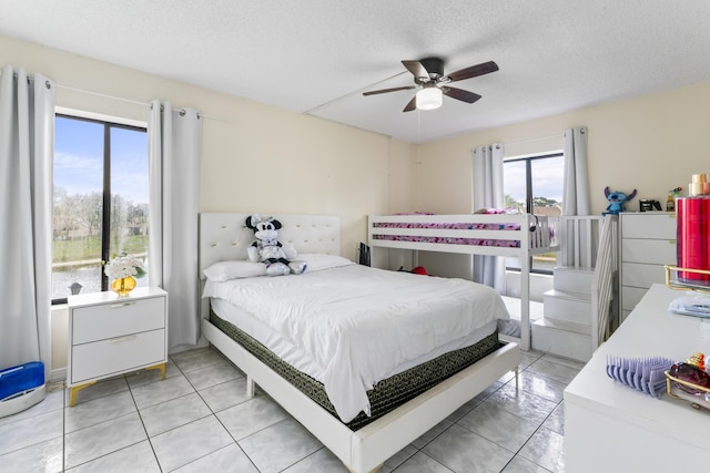 tiled bedroom with ceiling fan, multiple windows, and a textured ceiling