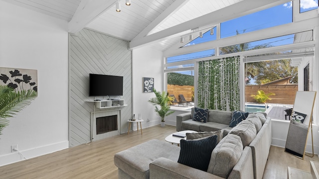 living room with beam ceiling, light hardwood / wood-style flooring, a large fireplace, and a high ceiling