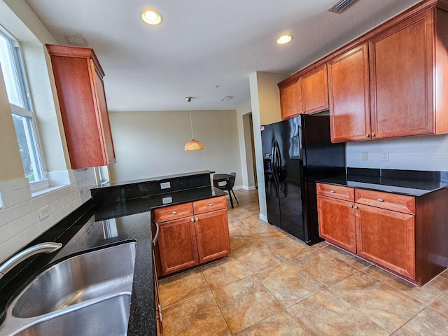 kitchen featuring decorative backsplash, sink, pendant lighting, and black fridge