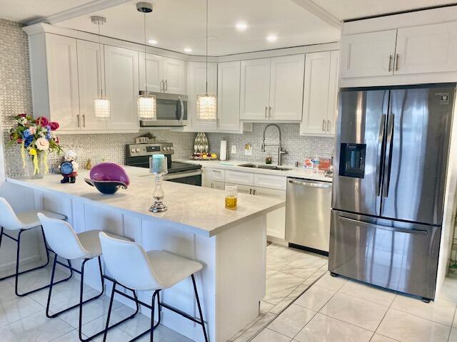 kitchen featuring pendant lighting, appliances with stainless steel finishes, sink, and white cabinets