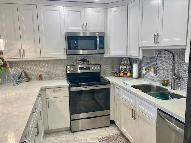 kitchen with tasteful backsplash, appliances with stainless steel finishes, and white cabinets