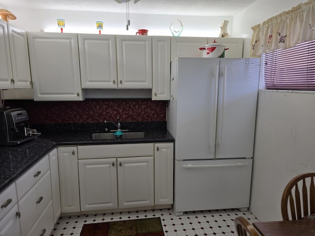 kitchen featuring sink, white cabinets, white fridge, and tasteful backsplash