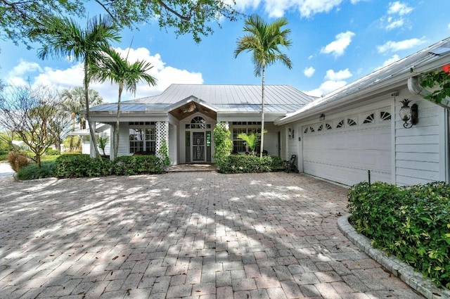 single story home with decorative driveway, metal roof, an attached garage, and a standing seam roof