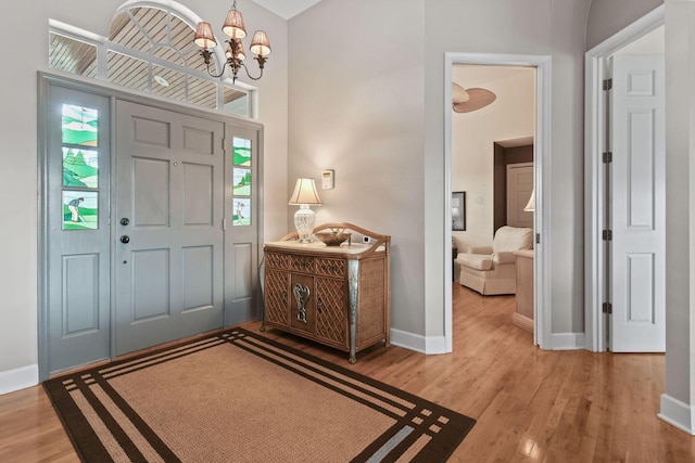 entryway with baseboards, a chandelier, and wood finished floors