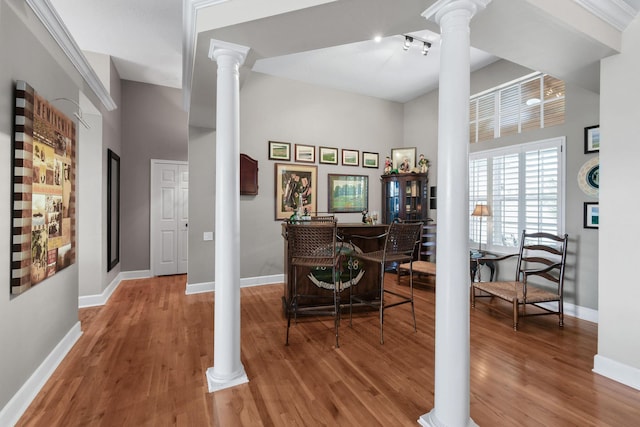 interior space featuring ornate columns, light wood-style flooring, and baseboards