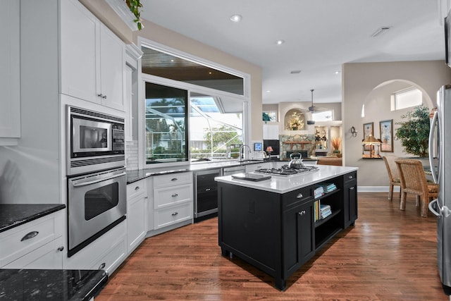 kitchen with appliances with stainless steel finishes, white cabinets, dark cabinetry, and a kitchen island