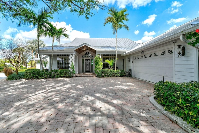 single story home featuring decorative driveway, metal roof, an attached garage, and a standing seam roof