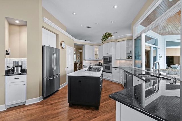 kitchen with dark wood finished floors, appliances with stainless steel finishes, a center island, open shelves, and a sink