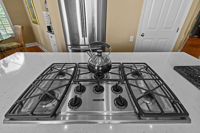 interior details featuring light stone counters, stove, and freestanding refrigerator