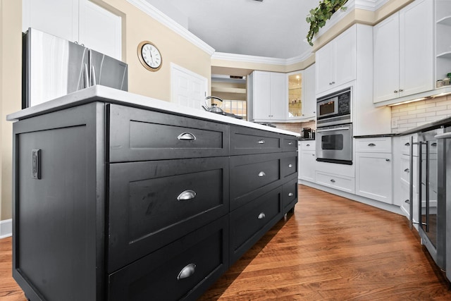 kitchen with crown molding, open shelves, tasteful backsplash, appliances with stainless steel finishes, and white cabinetry