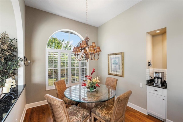 dining area featuring lofted ceiling, baseboards, a notable chandelier, and wood finished floors