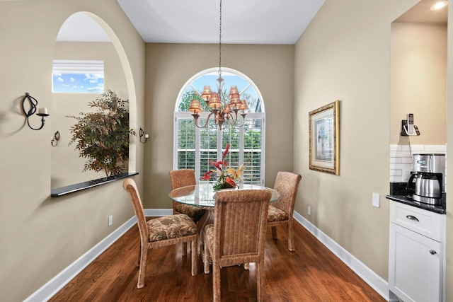 dining area with dark wood-style floors, a chandelier, and baseboards