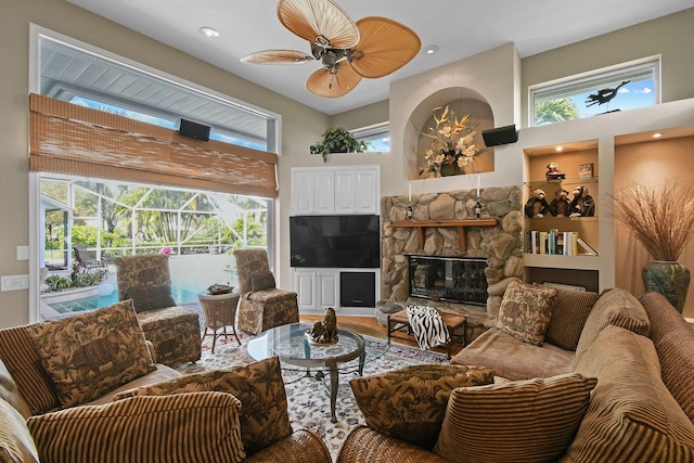 living area with built in features, a sunroom, ceiling fan, wood finished floors, and a fireplace