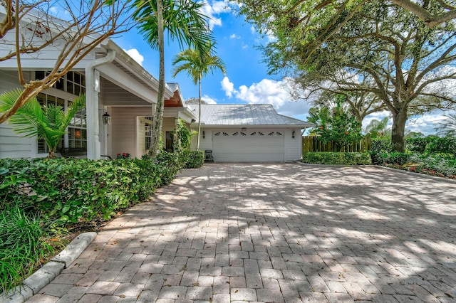 view of side of home with metal roof, decorative driveway, and an attached garage