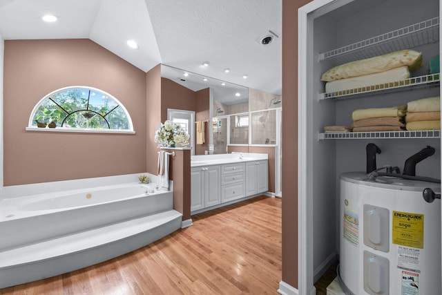 full bath featuring a stall shower, electric water heater, vaulted ceiling, vanity, and a bath