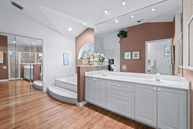 full bath featuring visible vents, wood finished floors, vaulted ceiling, a shower stall, and a sink