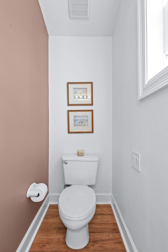 bathroom featuring toilet, baseboards, visible vents, and wood finished floors