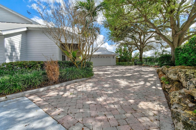 view of side of property featuring decorative driveway, metal roof, and an attached garage