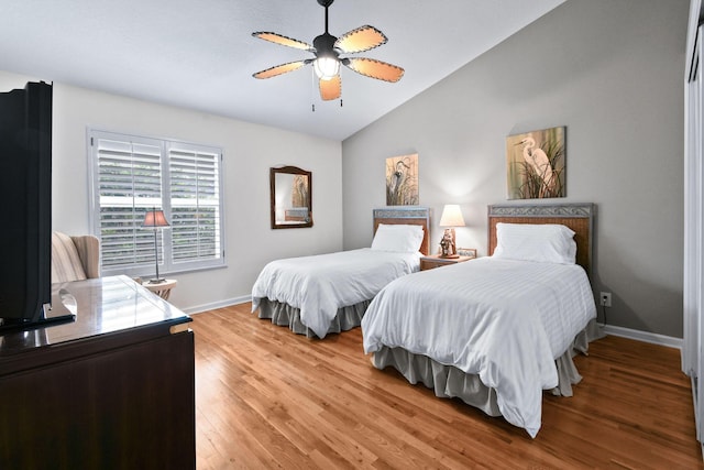 bedroom featuring a ceiling fan, light wood-type flooring, vaulted ceiling, and baseboards