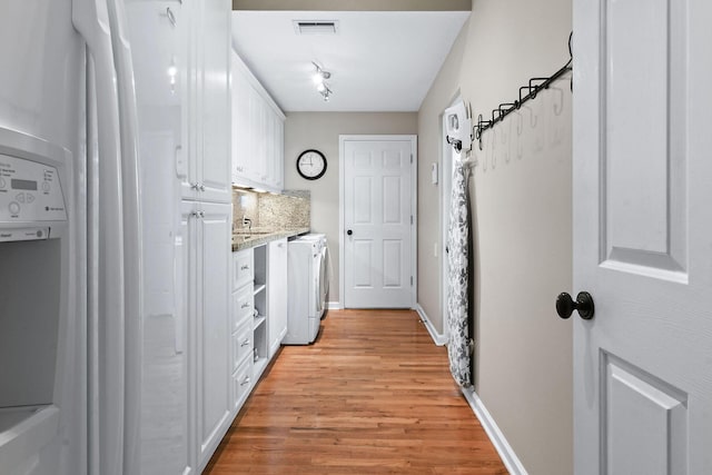 interior space featuring visible vents, light wood-style flooring, white cabinets, separate washer and dryer, and white fridge with ice dispenser