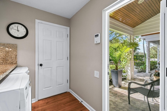 doorway to outside featuring lofted ceiling, baseboards, washer and clothes dryer, and dark wood finished floors