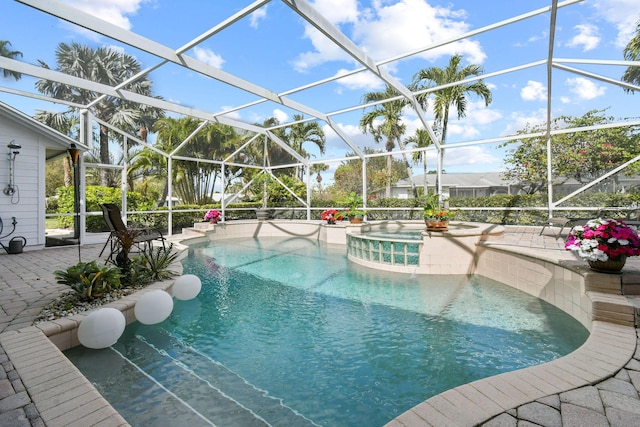 outdoor pool featuring a patio area, glass enclosure, and an in ground hot tub