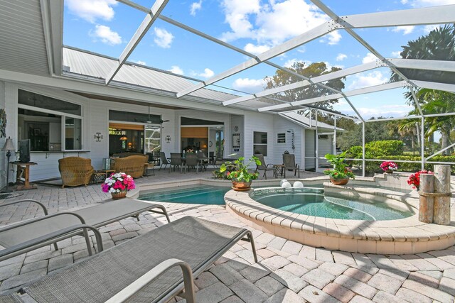 outdoor pool with a patio, outdoor dining area, glass enclosure, and an in ground hot tub