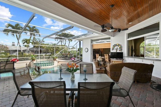 view of patio with outdoor dining space, a pool with connected hot tub, glass enclosure, and ceiling fan