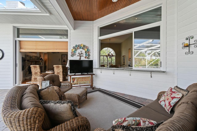 living room with wooden ceiling, wood walls, a skylight, a sunroom, and beamed ceiling