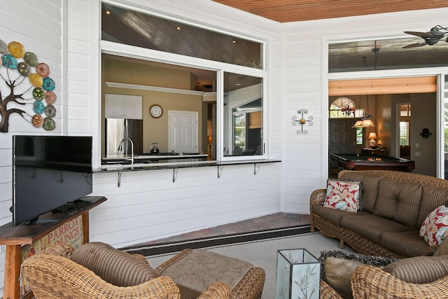 living room with concrete flooring, wood walls, and billiards