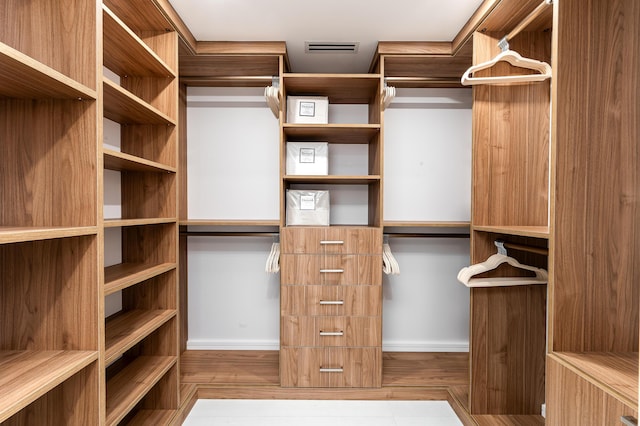 walk in closet with light hardwood / wood-style floors