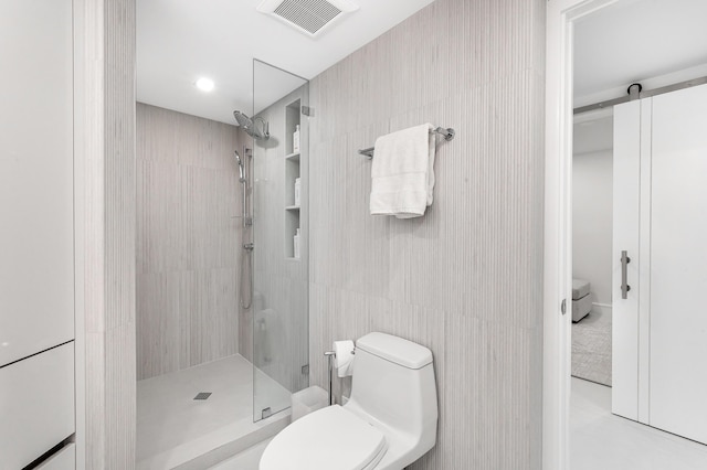 bathroom featuring a tile shower, tile walls, and toilet