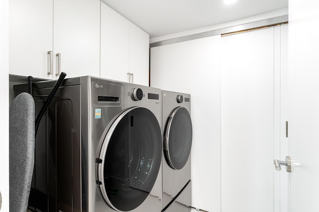 laundry area featuring washer and clothes dryer and cabinets