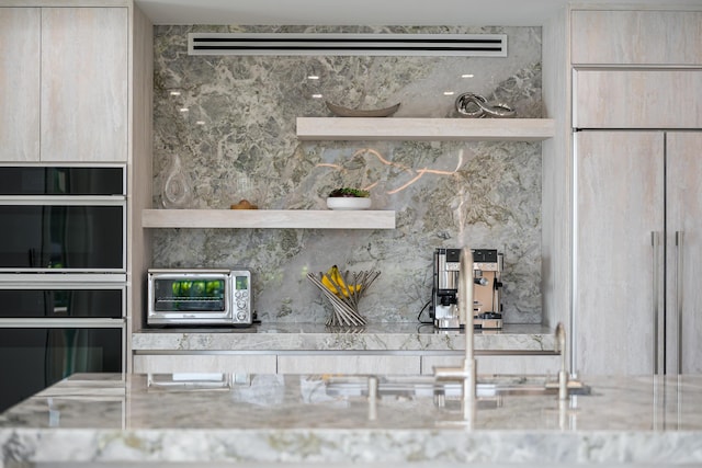 details with double wall oven, light brown cabinetry, light stone counters, and decorative backsplash