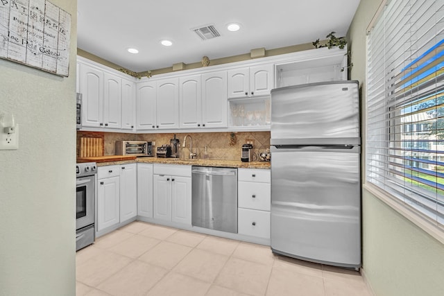 kitchen featuring appliances with stainless steel finishes, tasteful backsplash, white cabinetry, sink, and light stone countertops