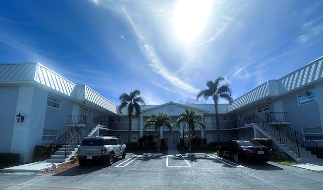 view of property with uncovered parking and stairway